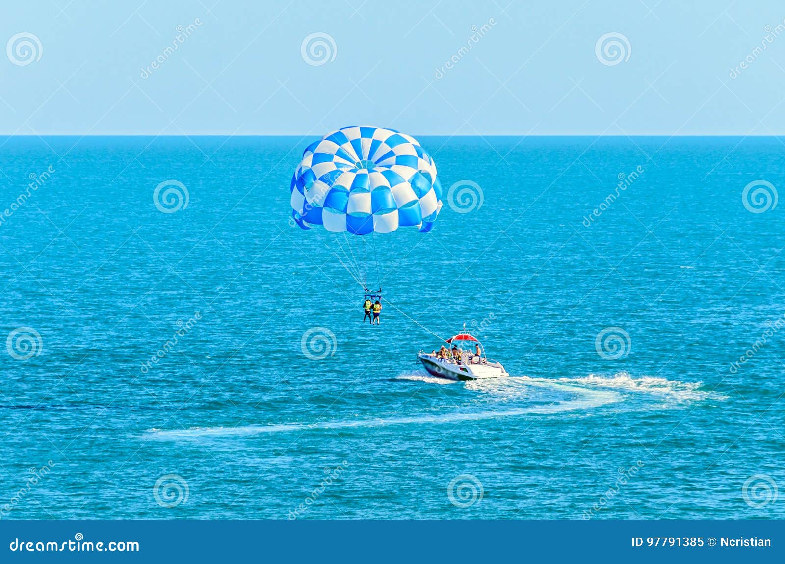 blue parasail wing pulled by a boat in the sea water, parasailing