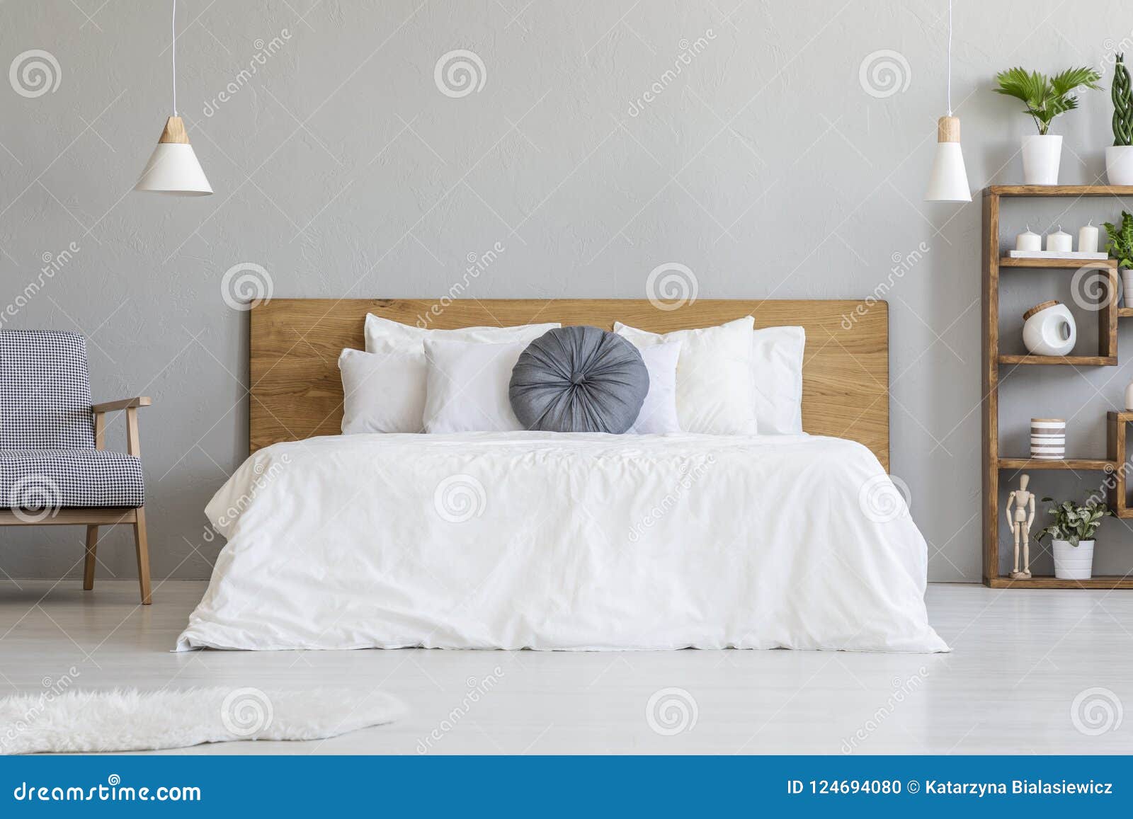 blue pillow on white bed with wooden headboard in bedroom interior with armchair. real photo