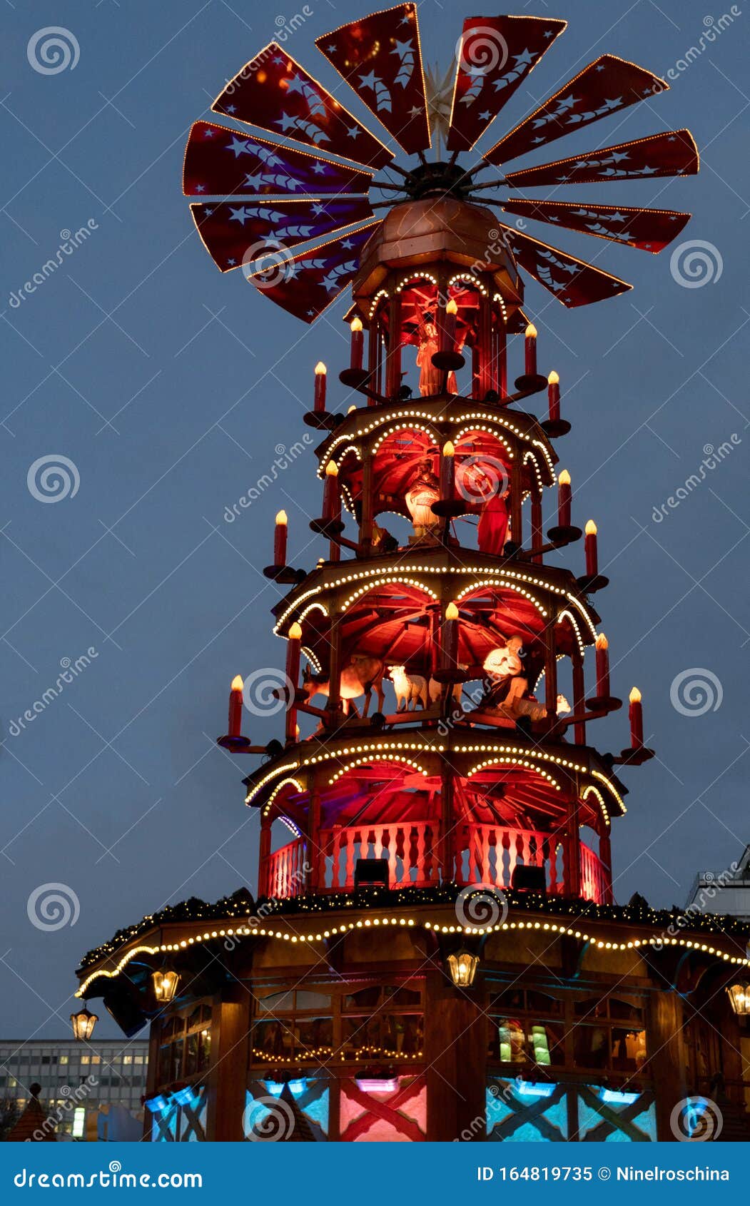 blue and red night christmas lights of traditional wooden carousel with catholic nativity scenes in berlin germany. fairy tale