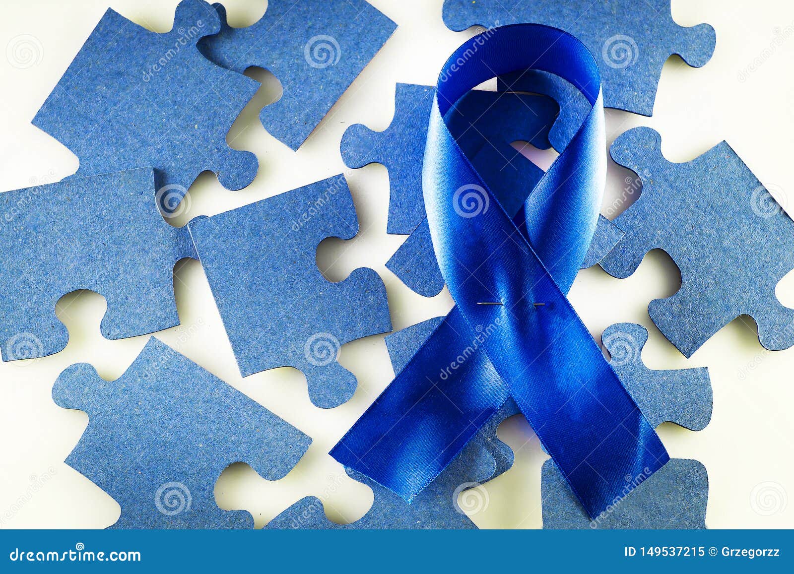 A Blue Ribbon on a Background of Scattered Jigsaw Puzzles Stock Image