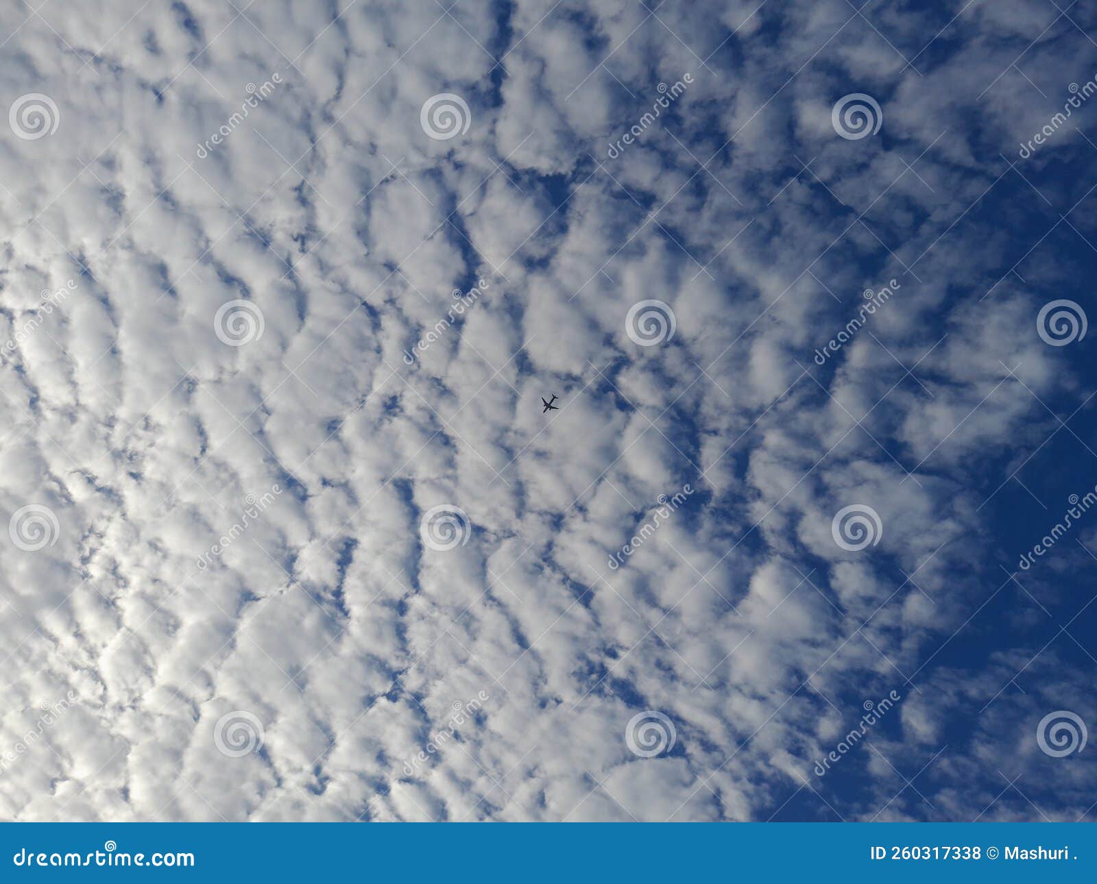 blue sky background with clouds. cirro-cumulus clouds on a blue sky on a sunny day. cirrus sky. the plane is crossing the clouds