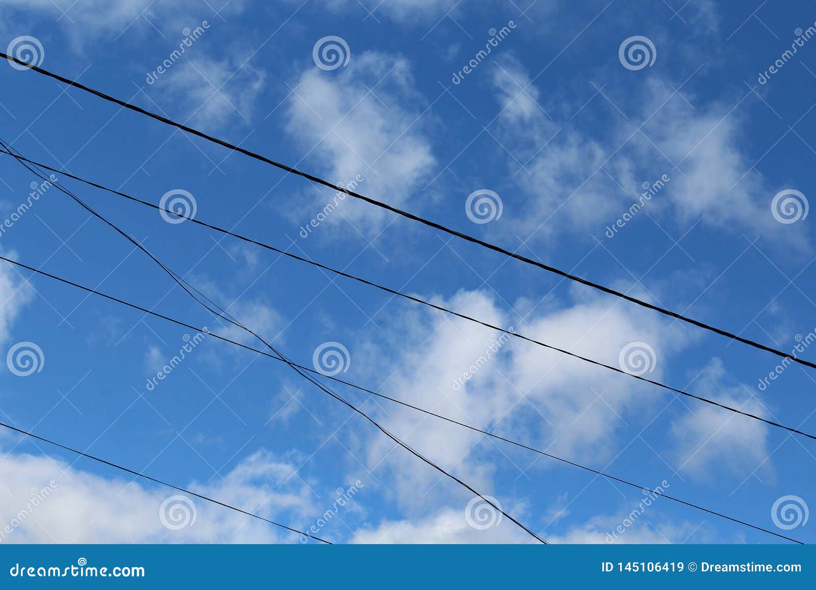 blue sky with white clouds and electric transmision wires, in the daytime.
