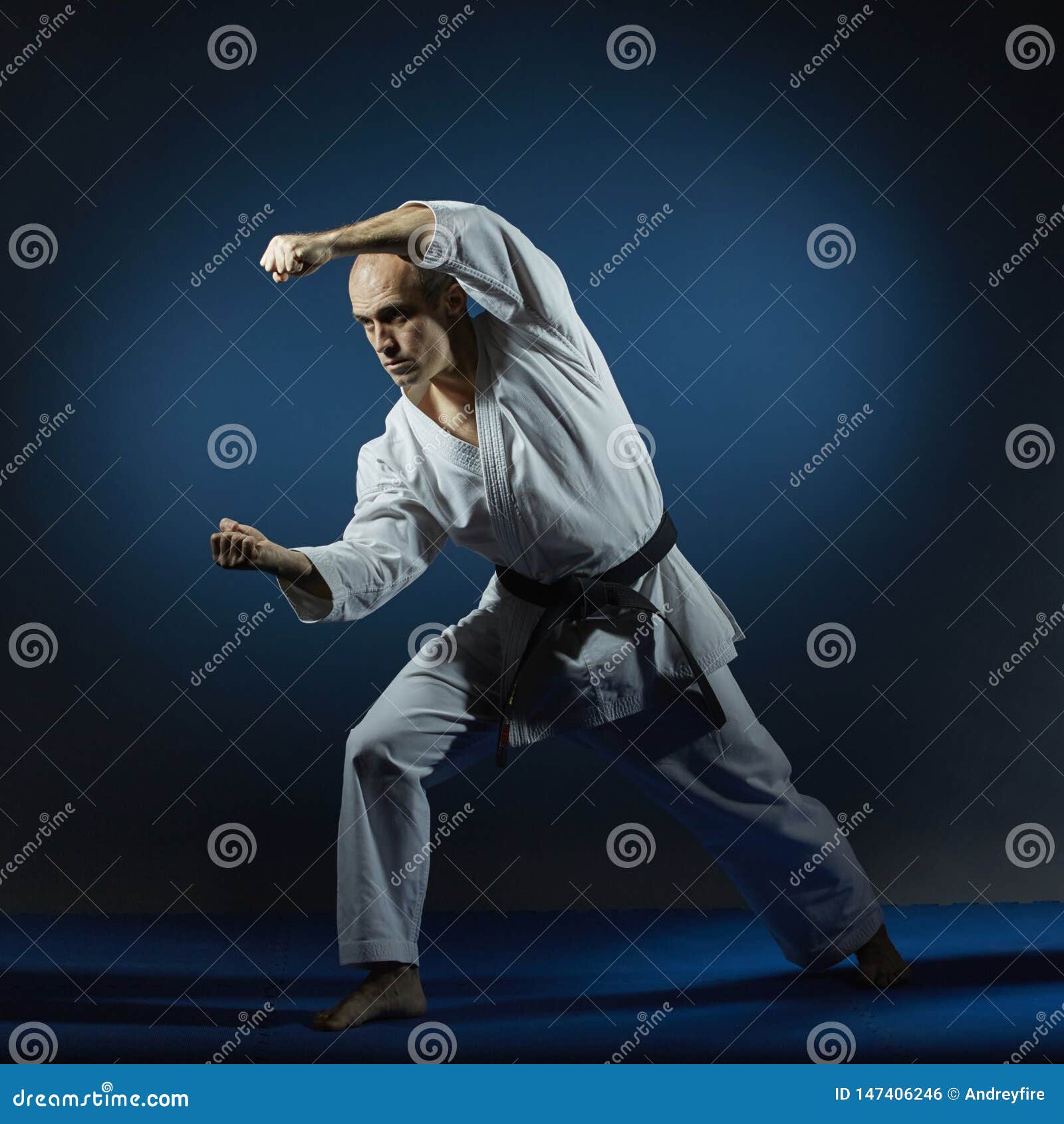 On the Blue Tatami Athlete Doing Formal Karate Exercises Stock Photo