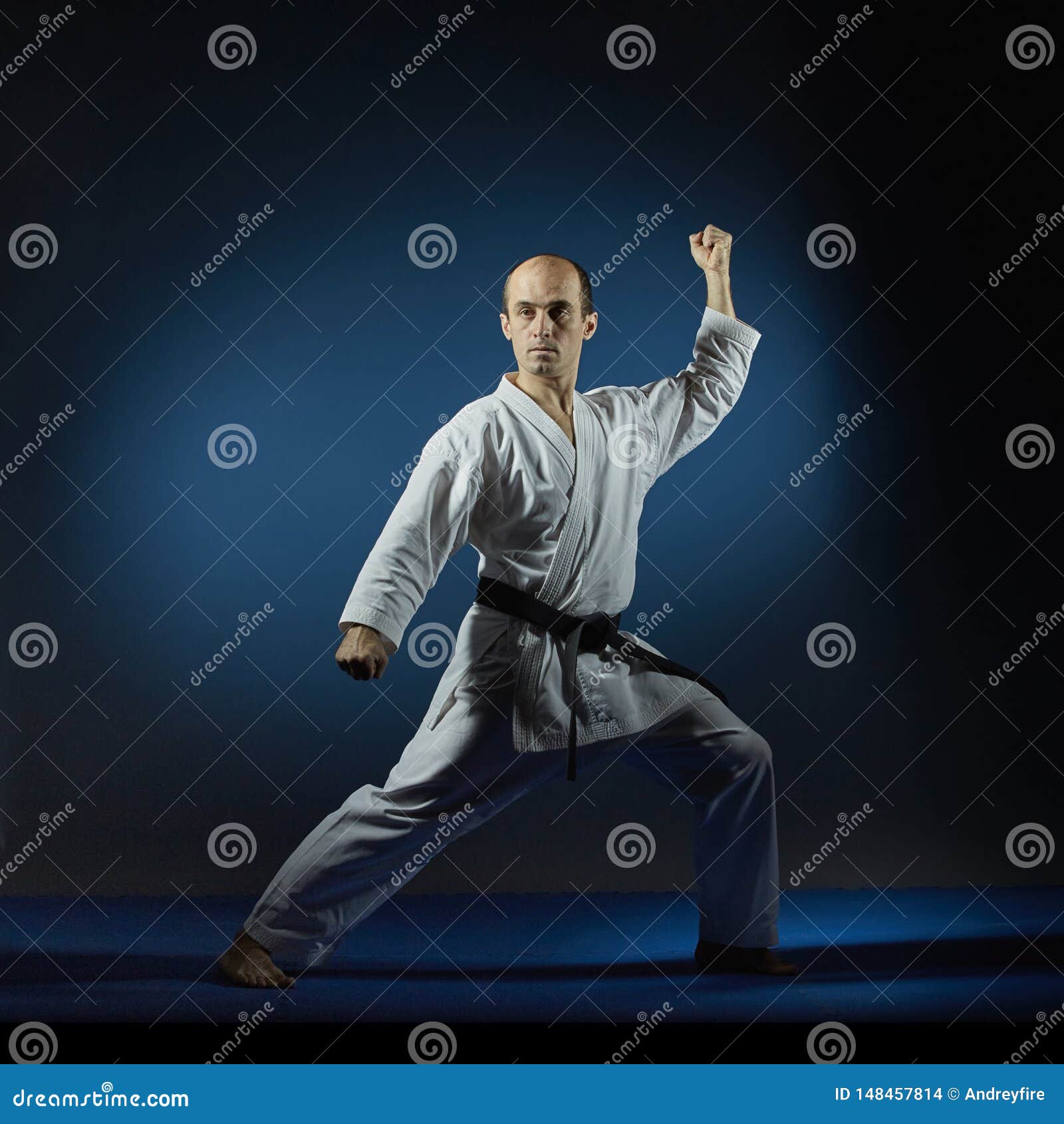 On the Blue Tatami Man Doing Formal Karate Exercises Stock Photo