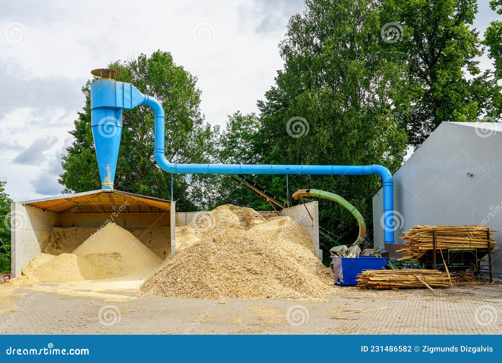 Blue Ventilation Pipe and a Stack of Sawdust Under it in the Sawmill