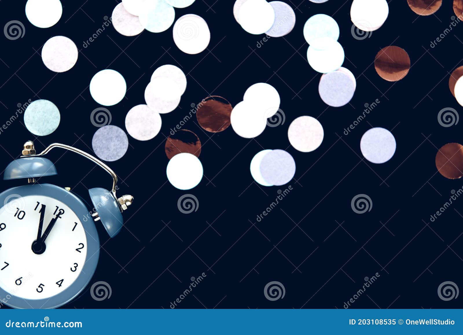 blue vintage alarm clock shows 12 o`clock  on dark background with sparkling round confetti metafan. wake up and hurry up