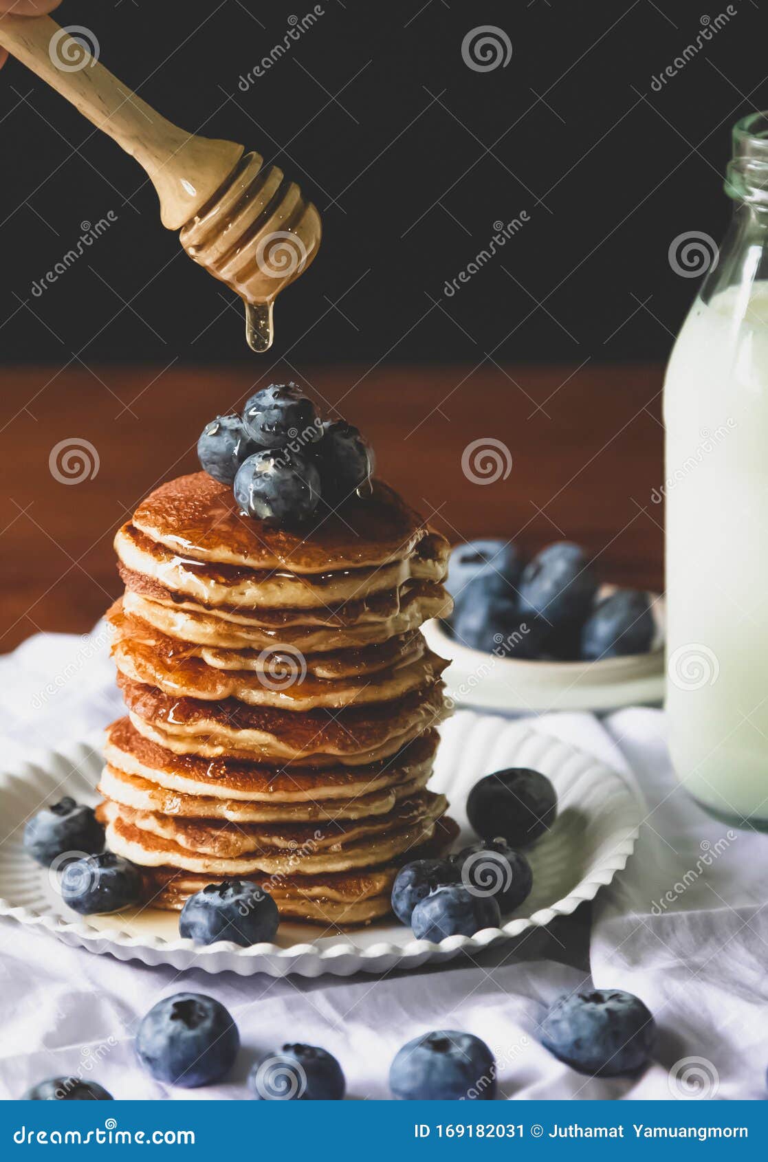 blueberry pancake homemade  and pouring   honey with milk  for a breakfast on wood table.vertical photo