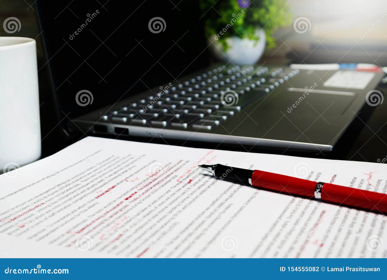 Blur proofreading sheet on table with red pen and laptop