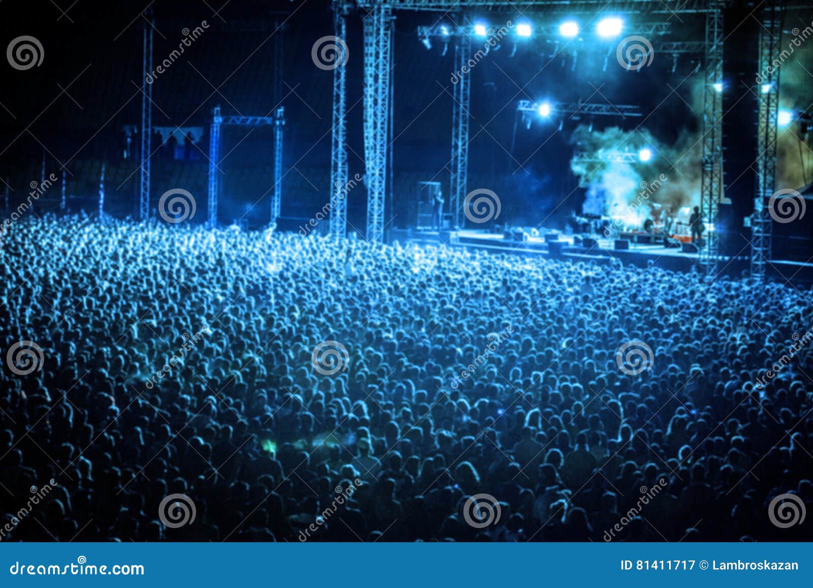 blurred image of huge crow of people at music concert, in blue t