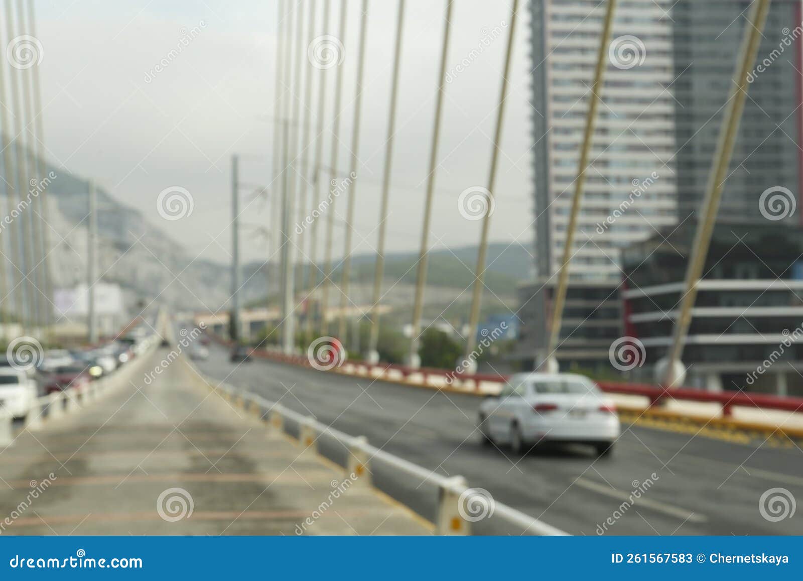 blurred view of modern bridge and cars near mountain