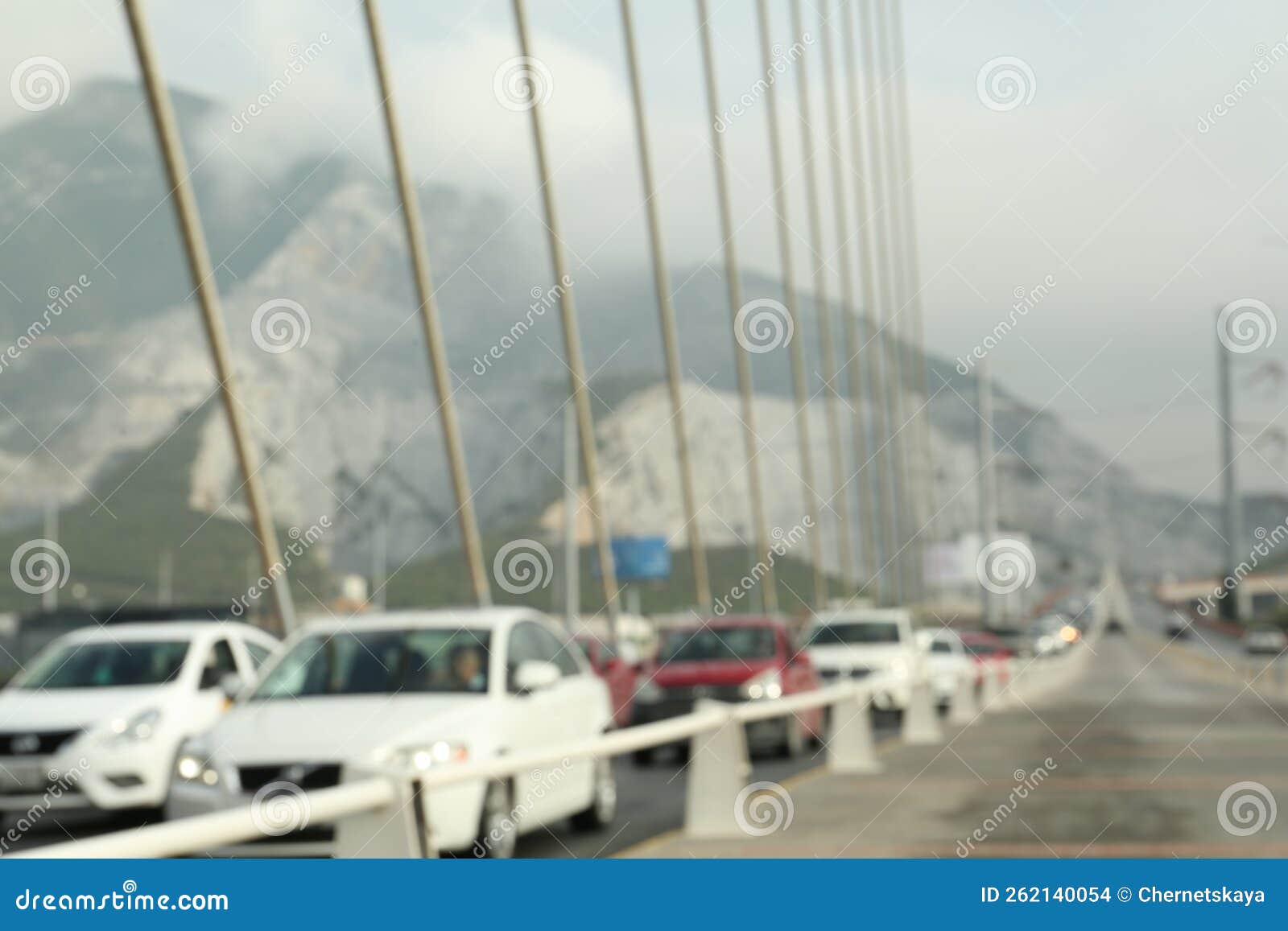 blurred view of modern bridge and cars near mountain