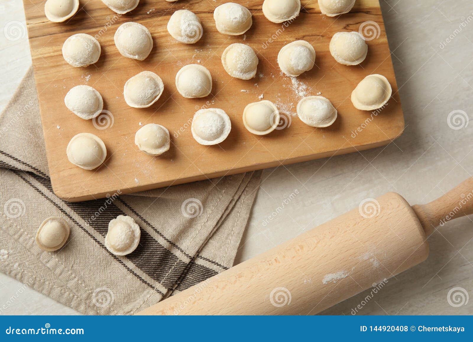 Board with Raw Dumplings and Rolling Pin on Light Background, Flat Lay