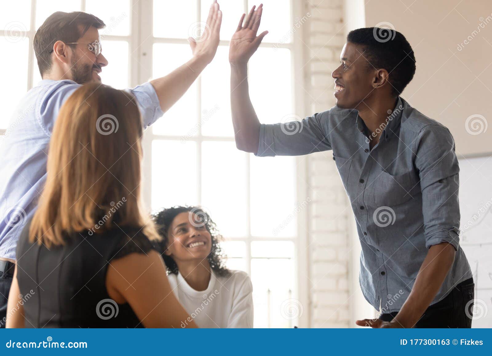 african and caucasian buddies giving high five greeting each other