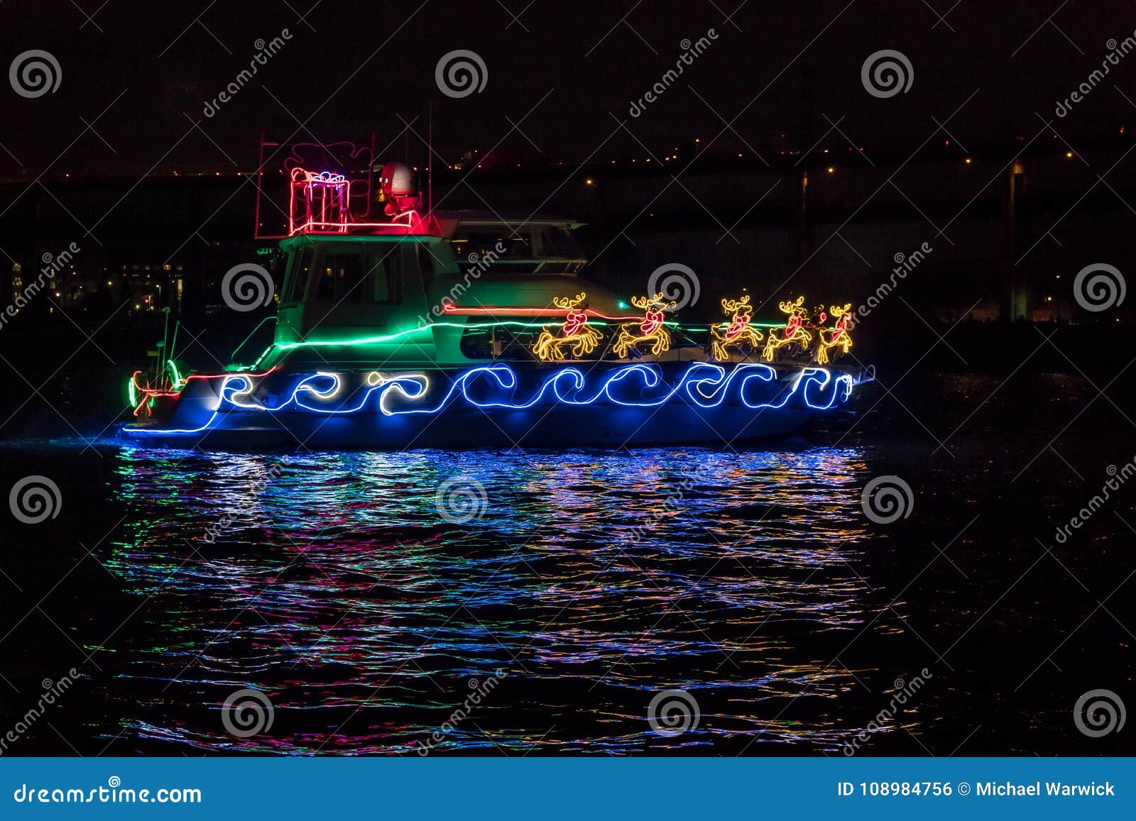 boat adorned with christmas holiday lights, santa claus sleigh and reindeer and reflection in the water.
