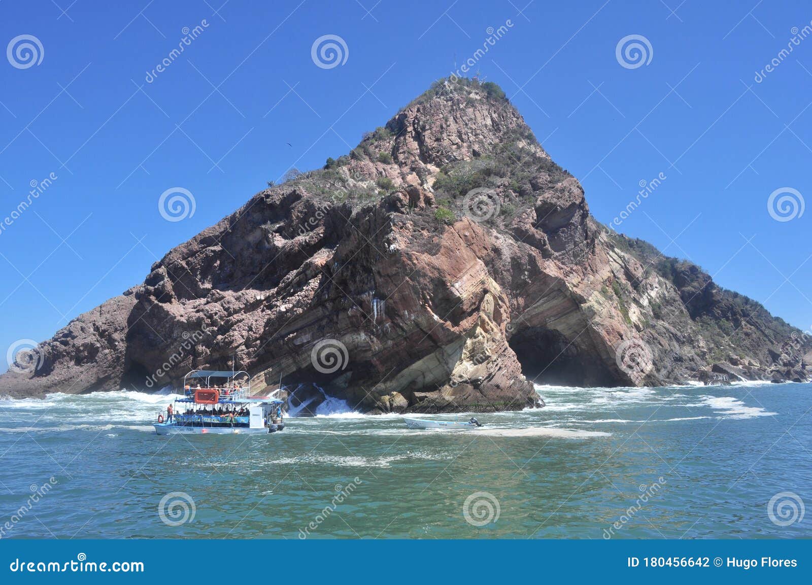 boat crossing in front of a large rock formation