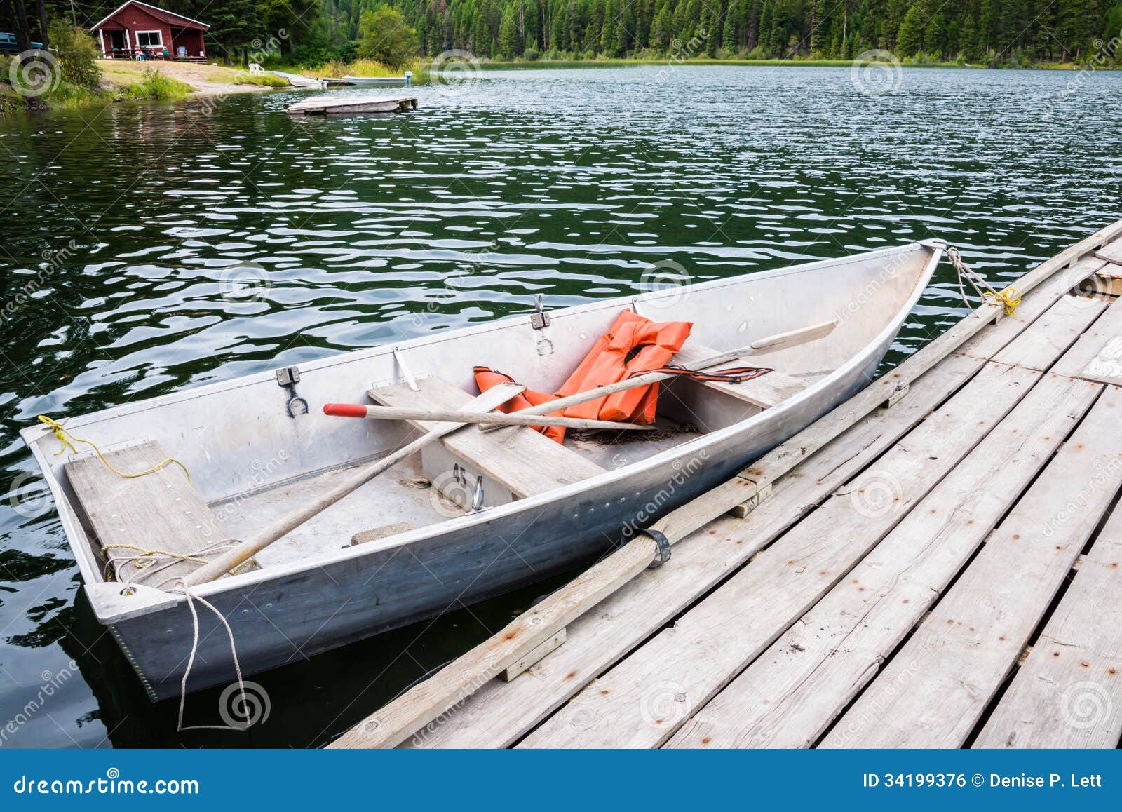 Old row boat with life jackets and oars moored to dock in lake. Copy 