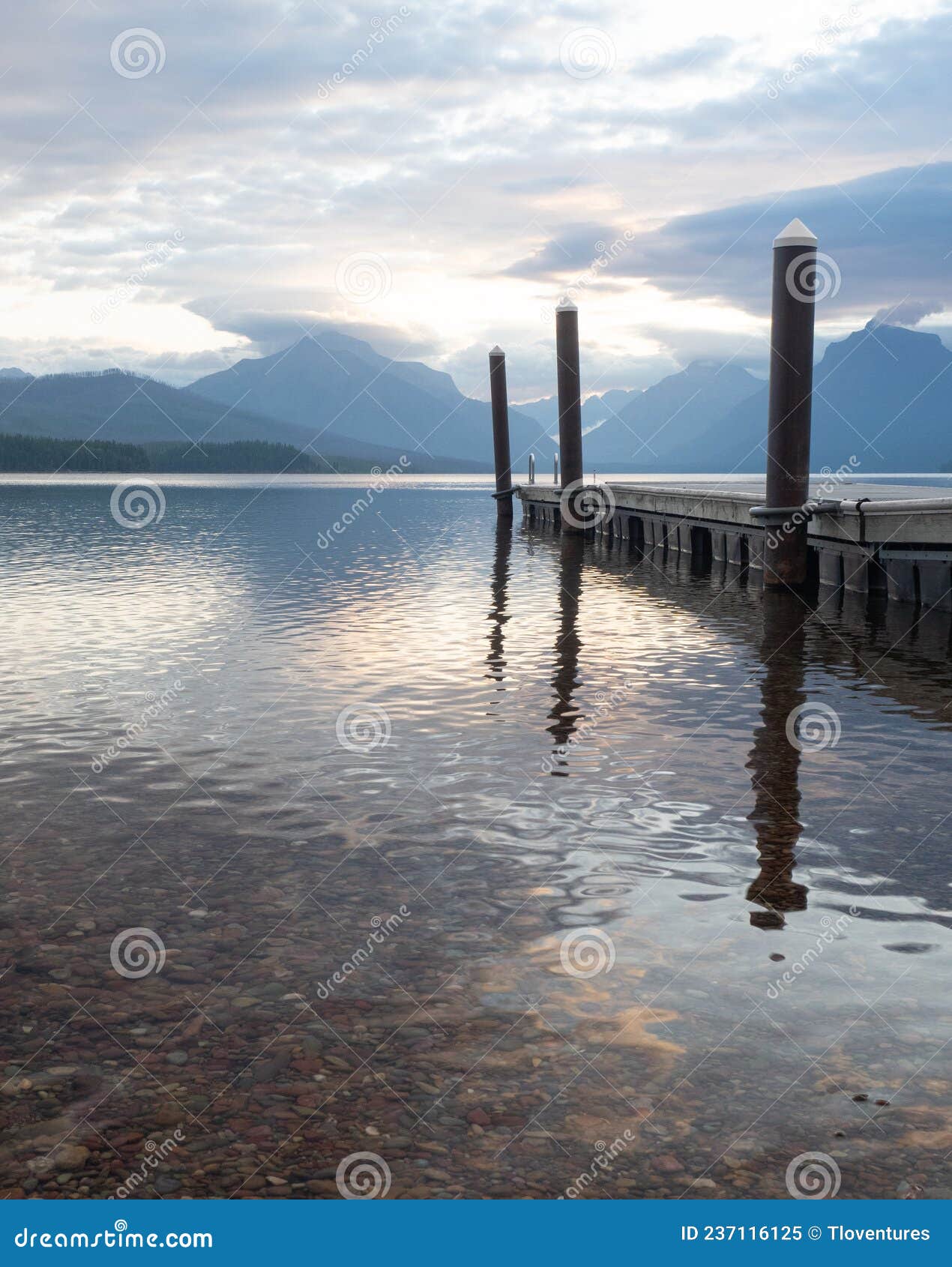 boat dock with reflection in lake mcdonald in glacier national park, montana, at dawn