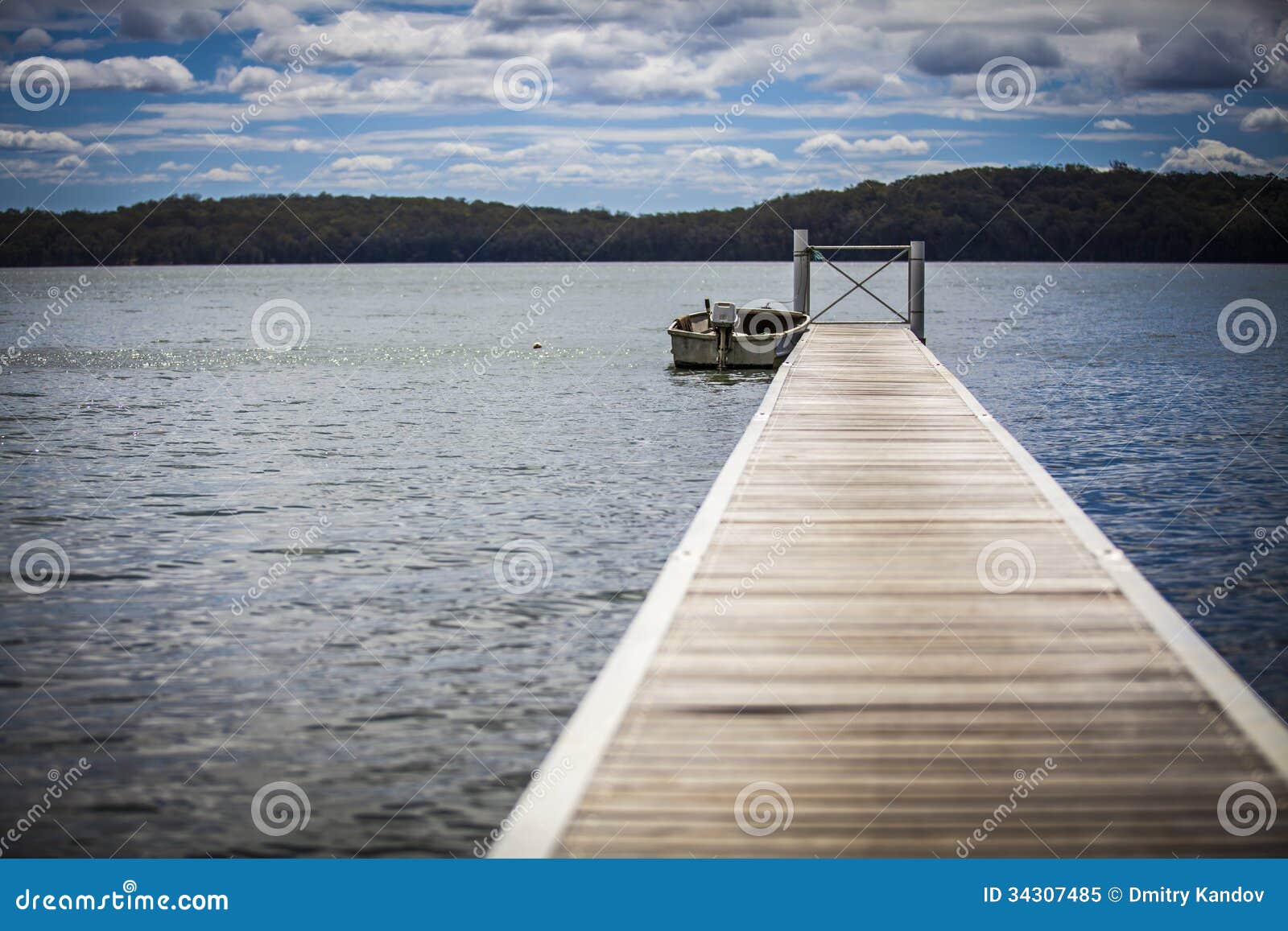 Boat at end of pier on lake. Scenic view of lake with boat at end of long pier.