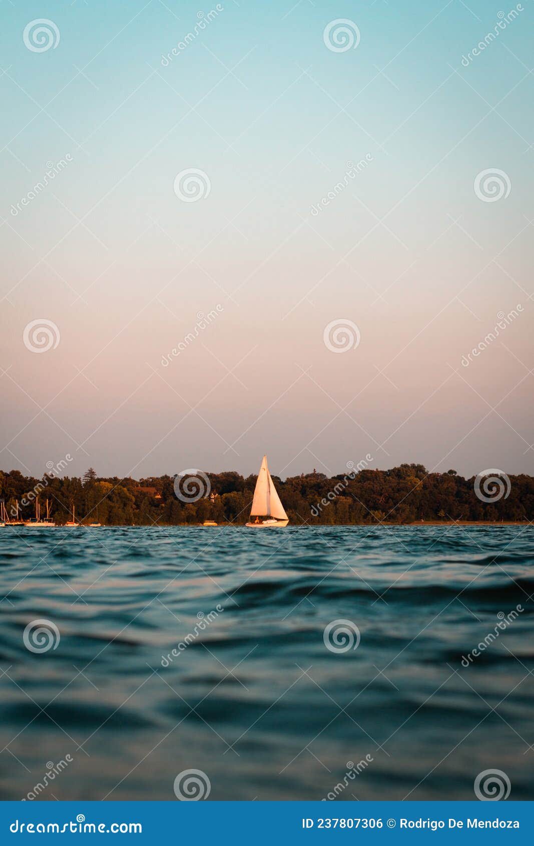 a boat sails across lake bde maka ska (formerly known as lake calhoun) in minneapolis, mn at sunset