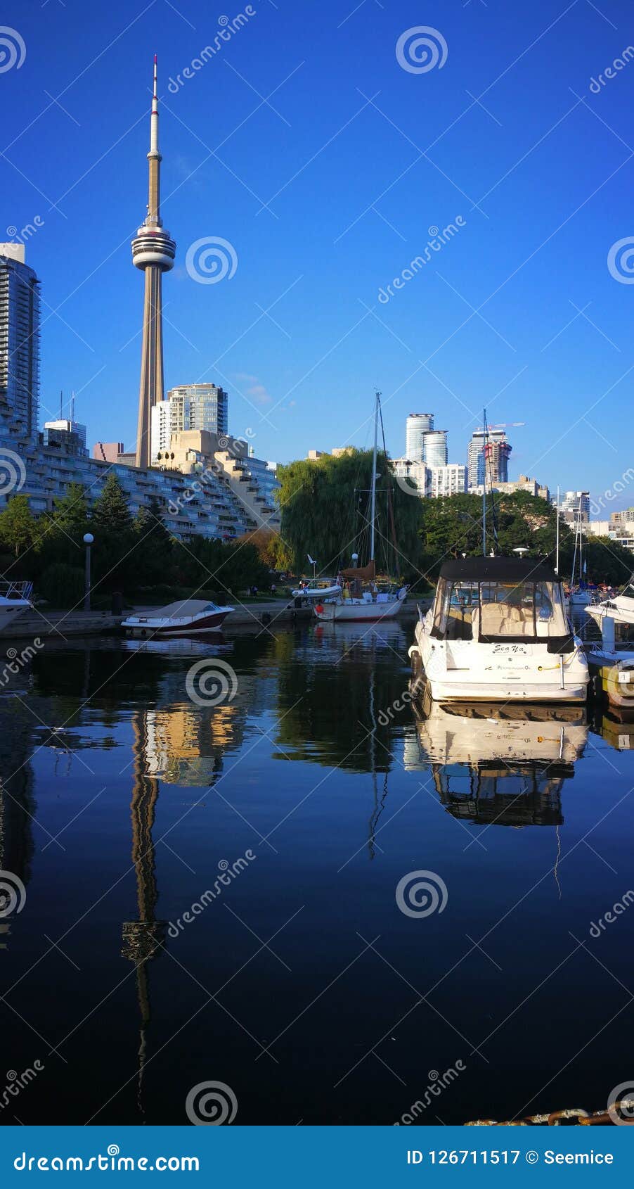 Boats on the Lake Ontario, Canada. Dark blue lake, light blue sky fill, light white clouds, leisurely fishing boats.