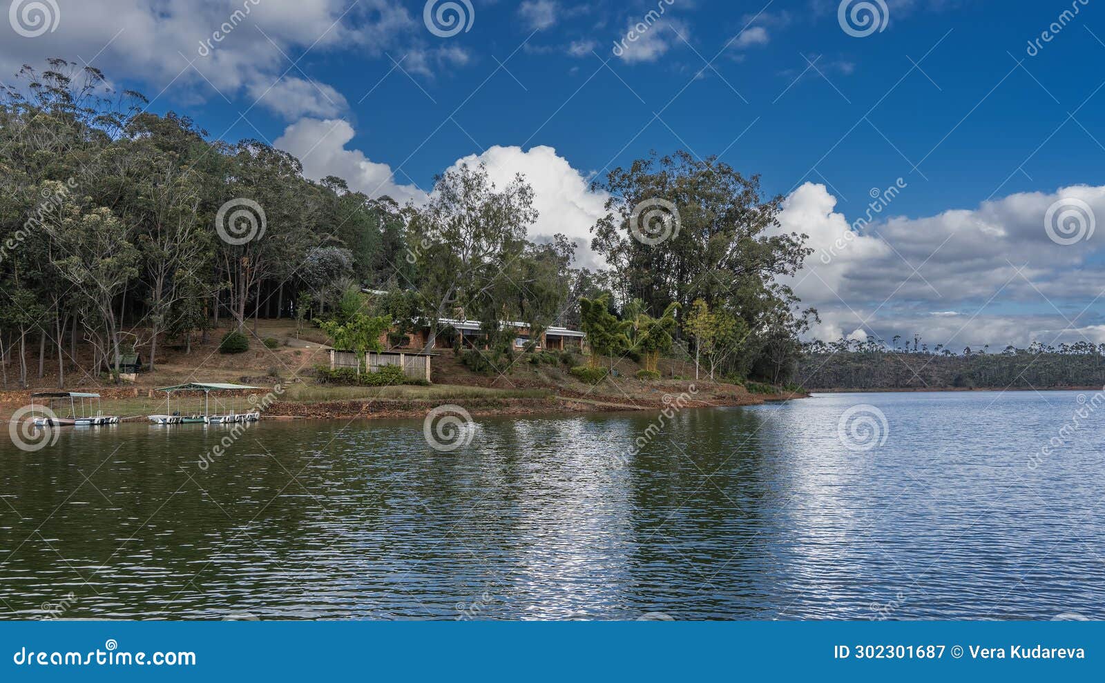 the boats are moored at the shore of a calm lake.