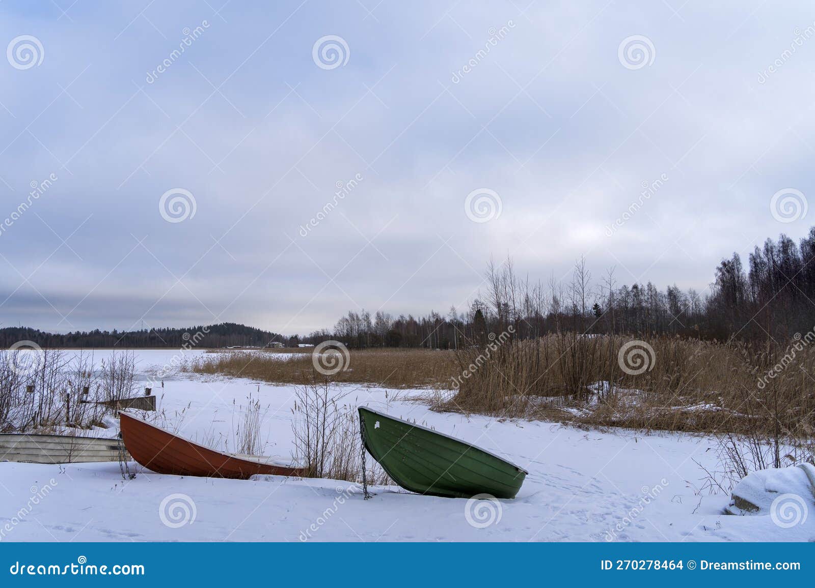 boats on the shore of a frozen lake in finland. winter landscape, copy space