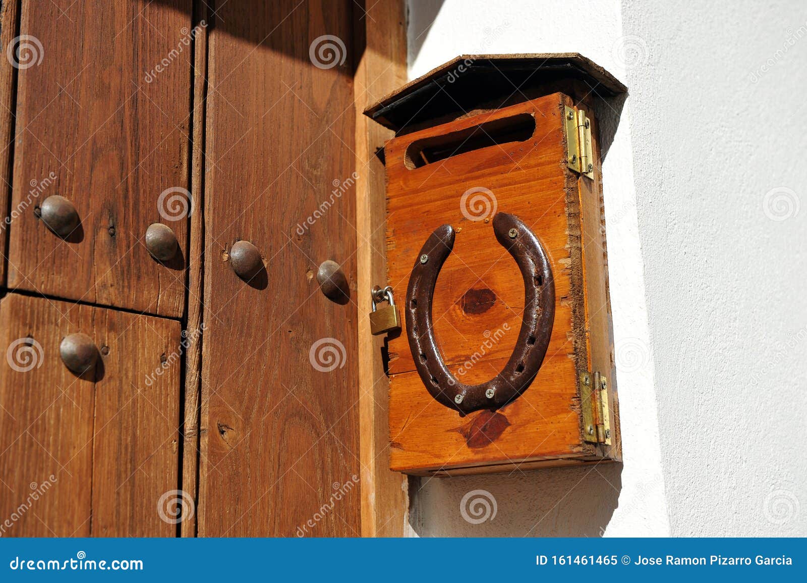 buzon de cartas de madera con candado y herradura en la fachada de una vivienda unifamiliar