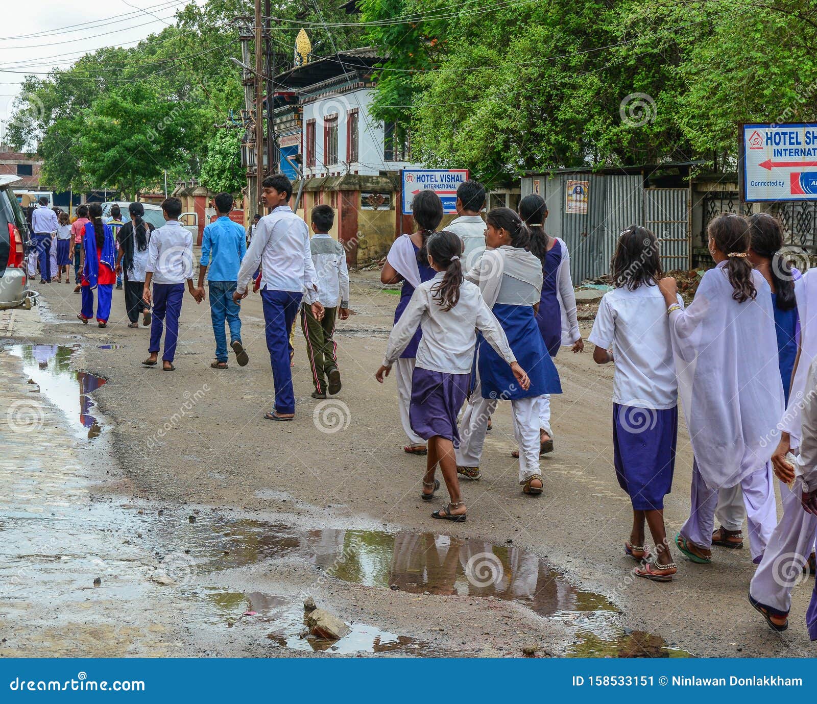 Highschool students walking on road. Bodhgaya, India - July 9, 2015. Highschool students walking on rural road in Bodhgaya, India. Bodh Gaya is the most revered of all Buddhist sacred sites