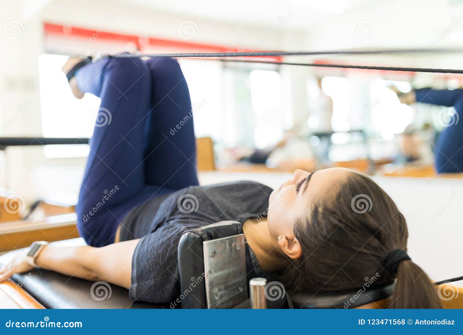 body conscious woman exercising on pilates reformer machine