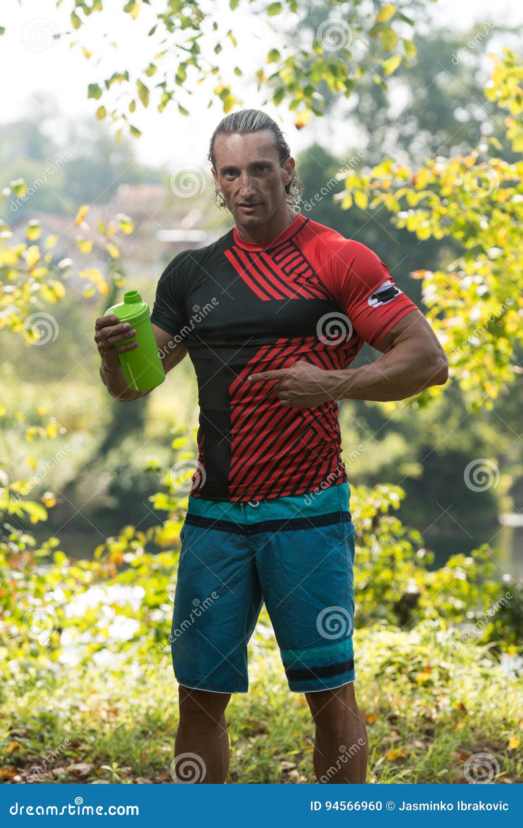 Bodybuilder Drinking Water from Shaker Outdoors in Nature Stock Photo
