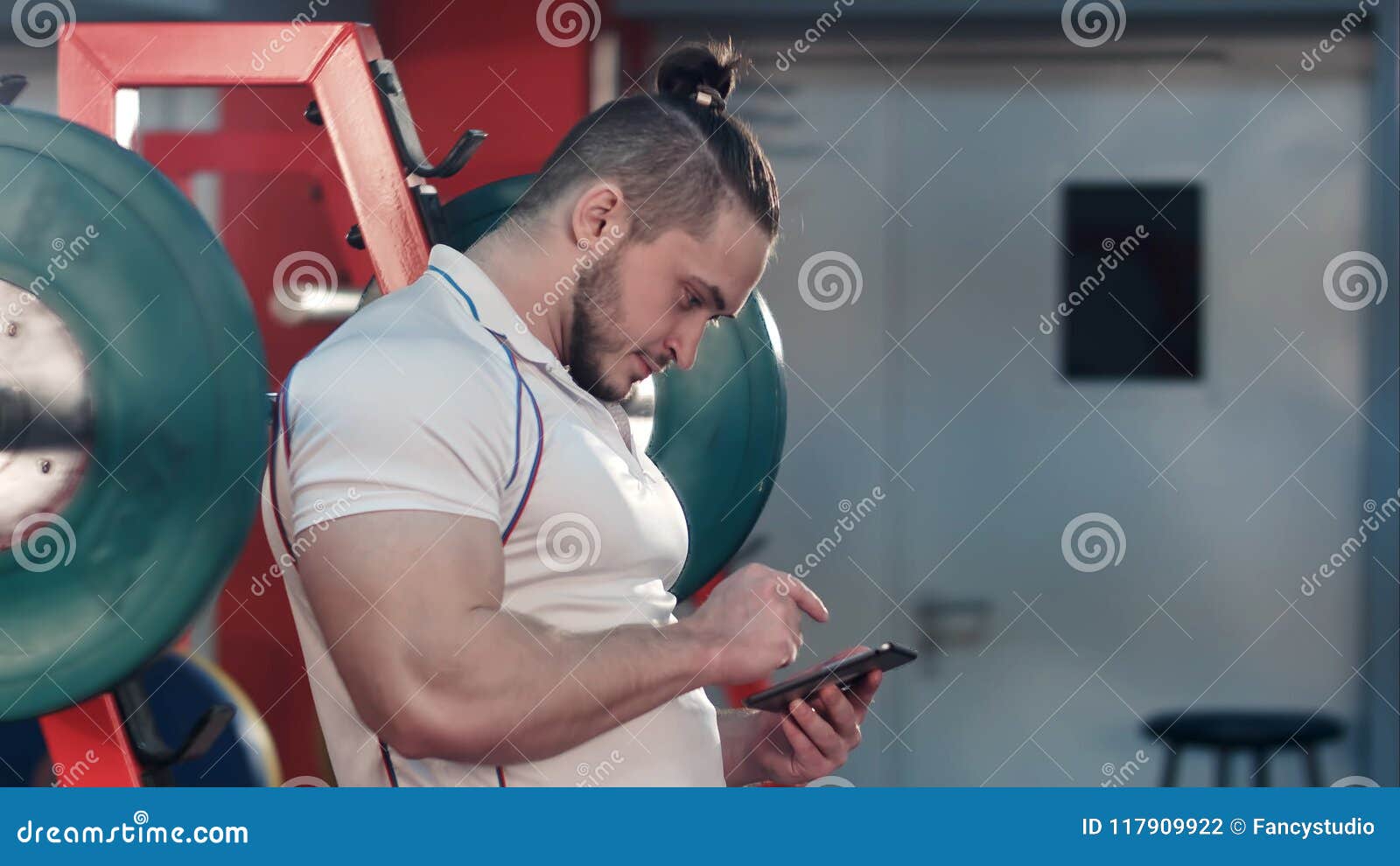Bodybuilder Using Digital Tablet To Track His Workout Progress in Gym