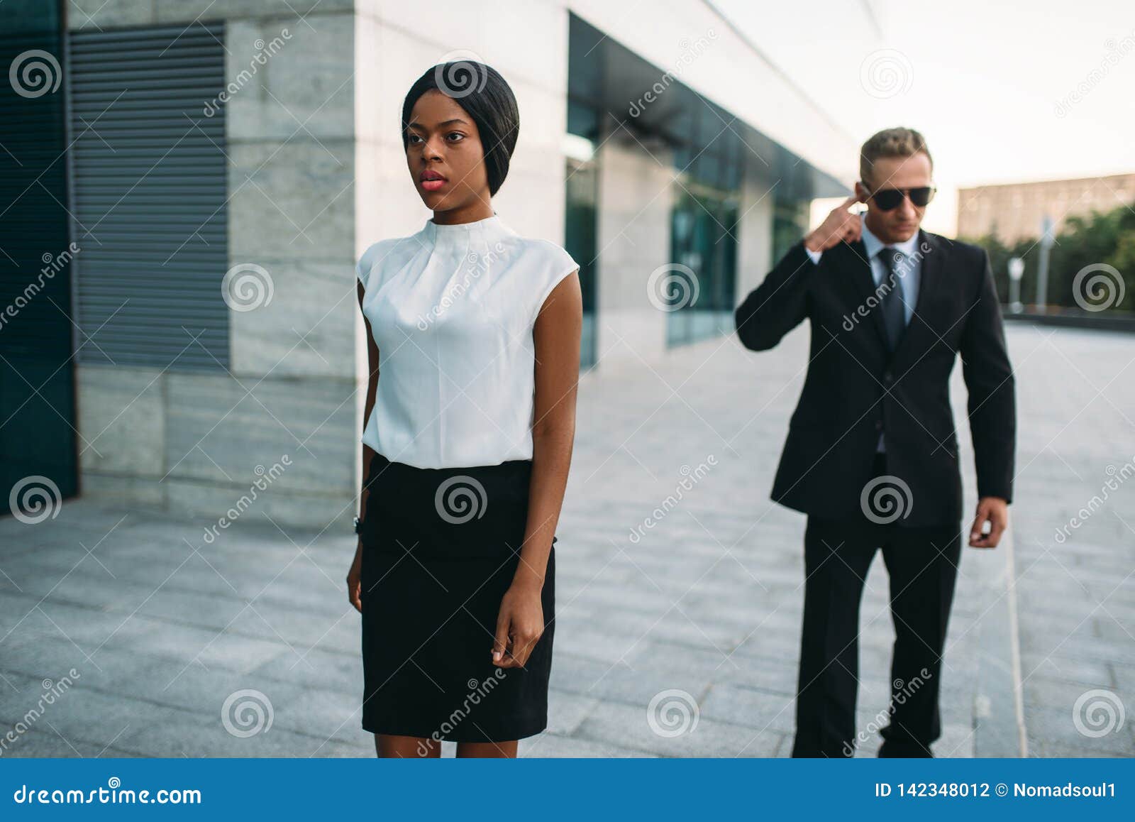 Serious Bodyguard Standing with Sunglasses and Security Earpiece