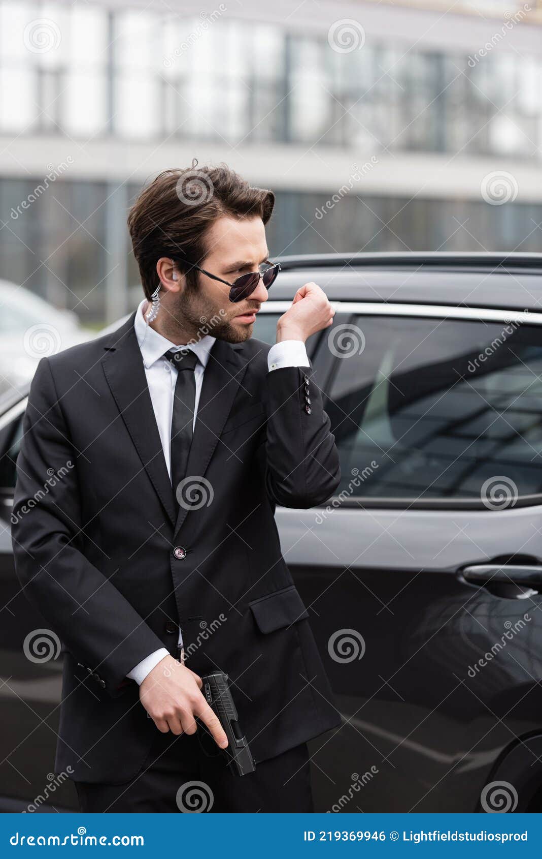 Serious Bodyguard Standing with Sunglasses and Security Earpiece