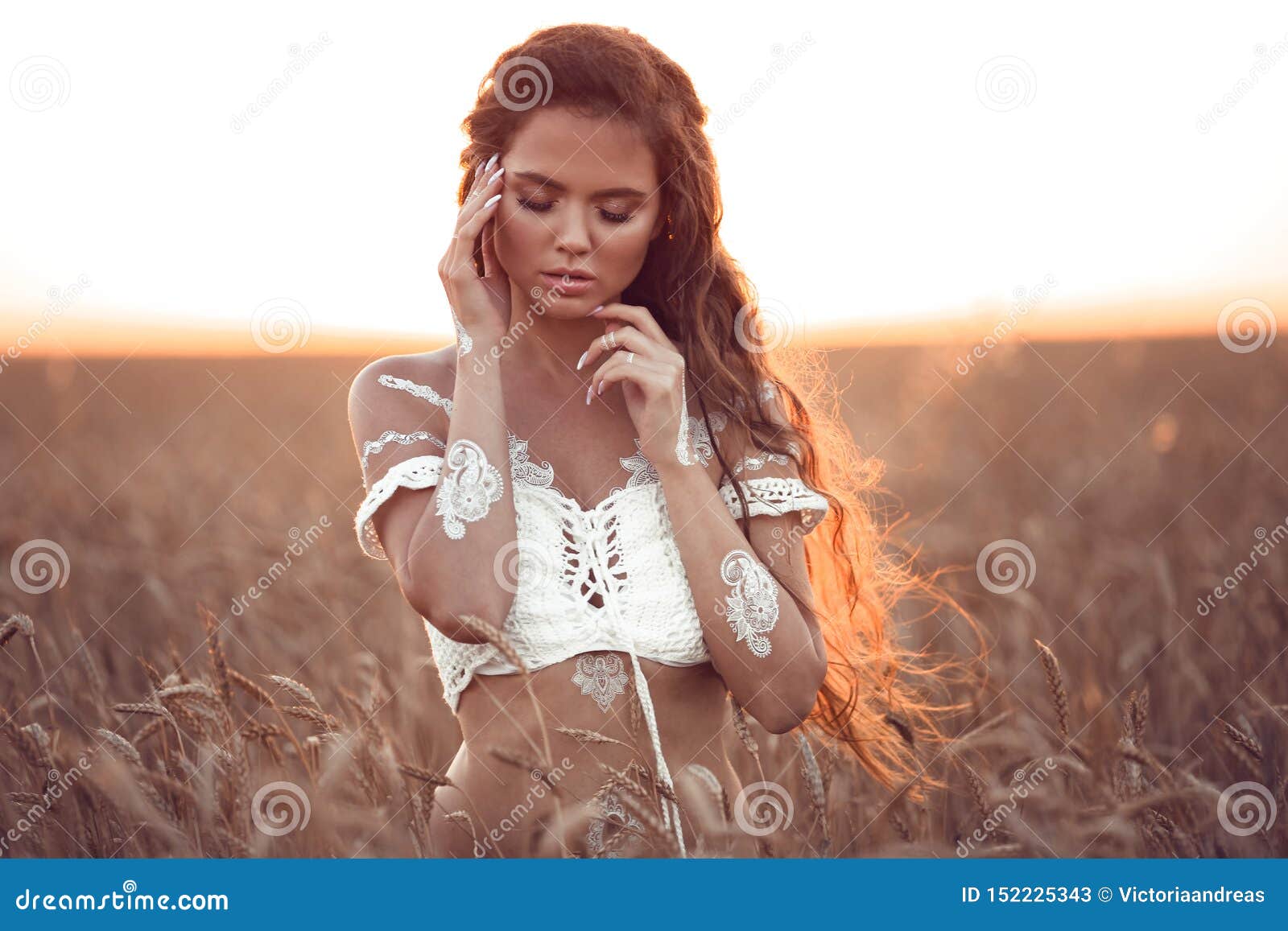 boho chic style. portrait of bohemian girl with white art posing over wheat field enjoying at sunset. outdoors photo. tranquility