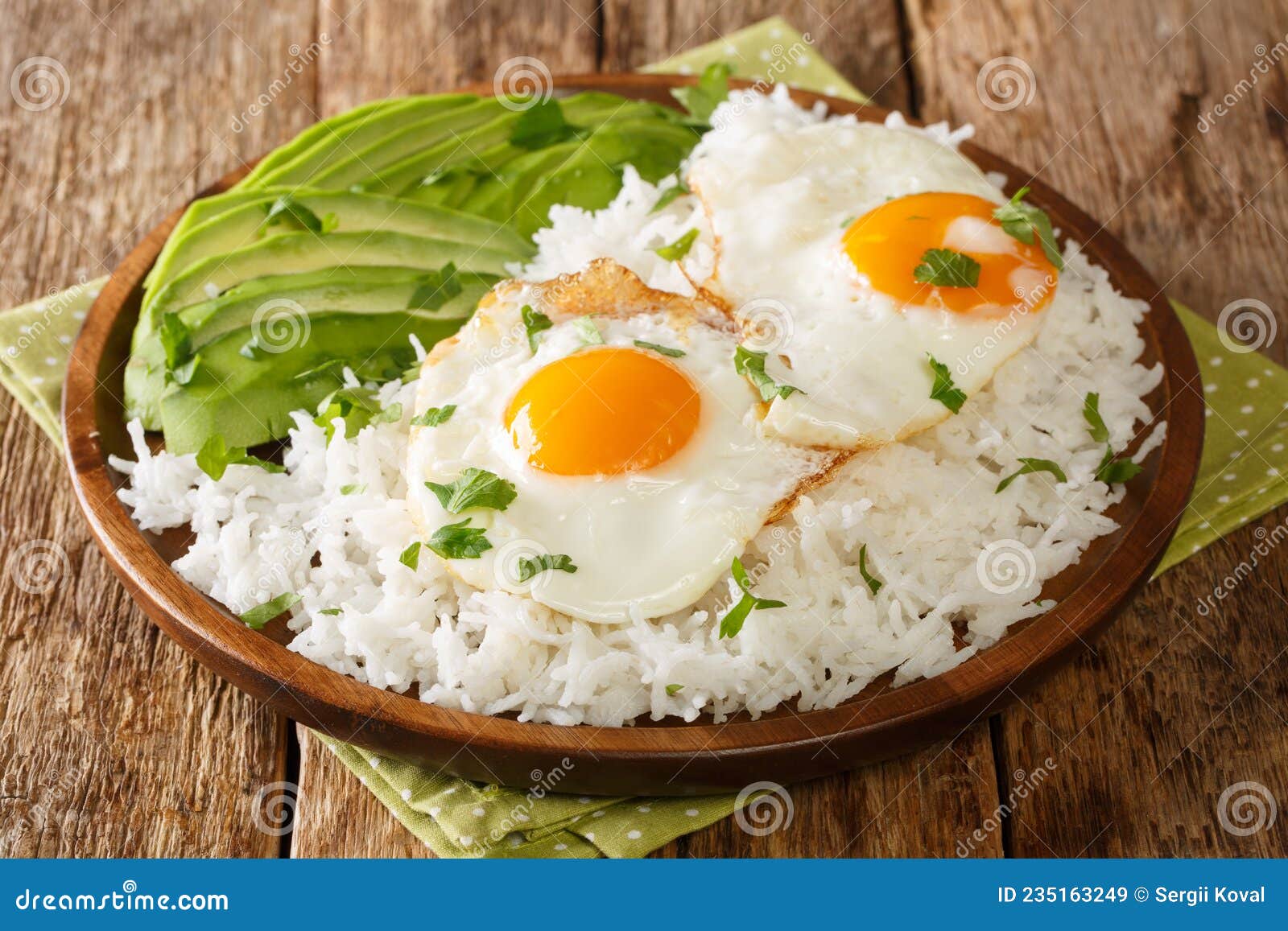 boiled rice on top with fried eggs served with fresh avocado close-up in a plate. horizontal