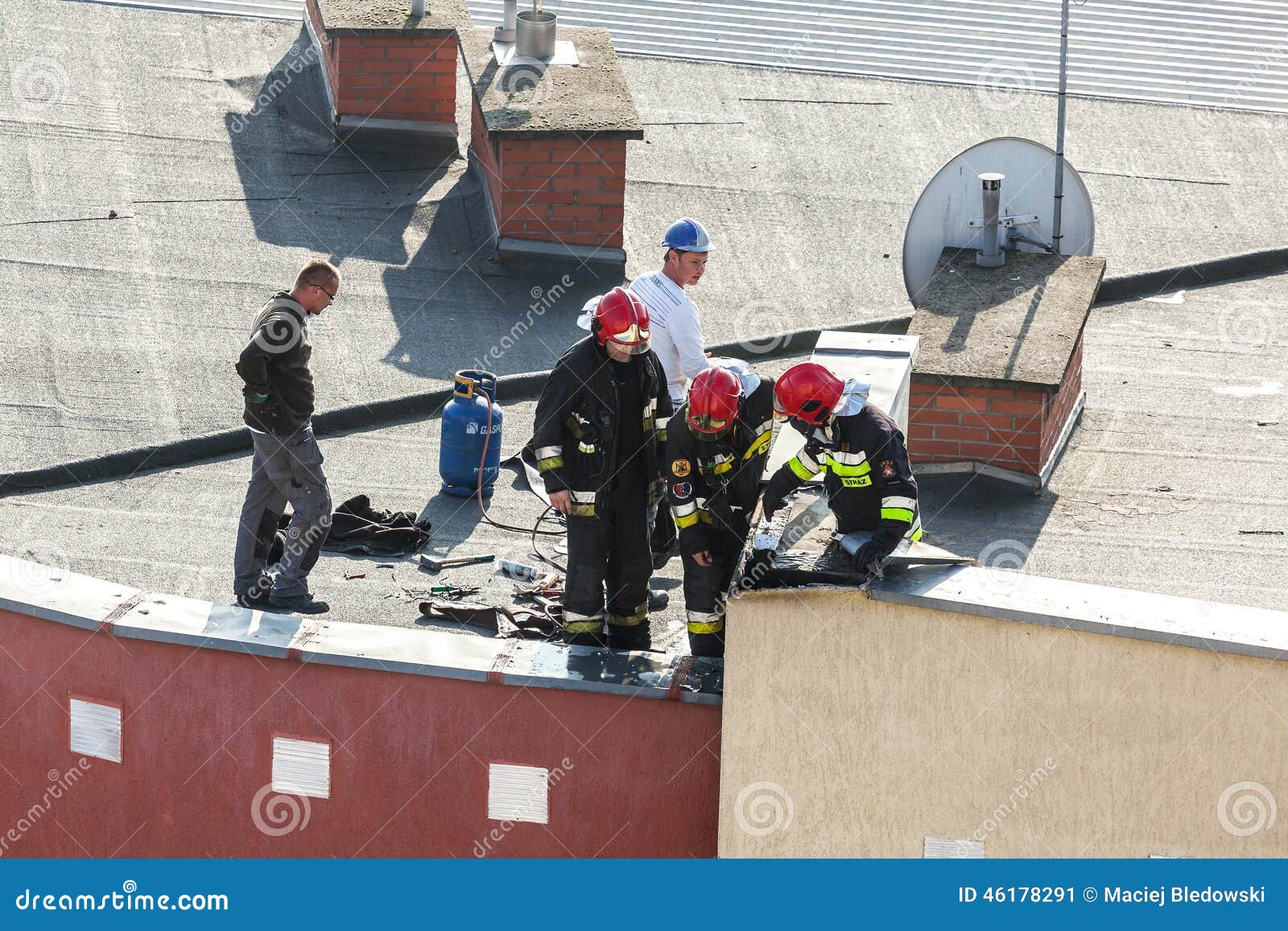 Szczecin, Polonia - 29 de octubre de 2014 - bomberos que comprueban la chimenea de un sistema de calefacción en el tejado del apartamento en la calle de Niemierzynska