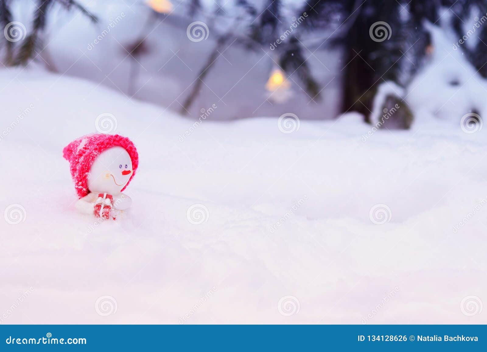 Bonhomme De Neige Drole De Jouet De Noel Dans Un Chapeau Rose Lumineux Se Reposant Dans Une Congere Avec Un Cadeau Sous L Arbre E Photo Stock Image Du Cadeau Felicitez