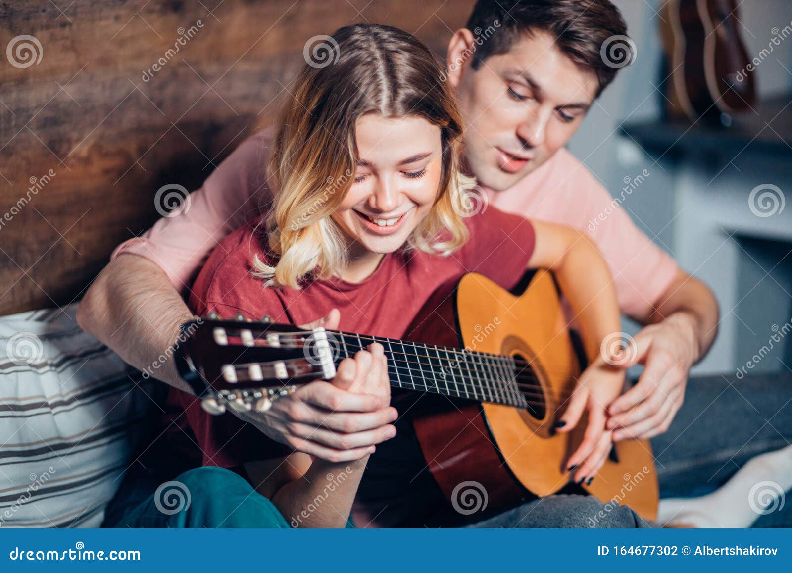 https://thumbs.dreamstime.com/z/bonita-pareja-descansando-en-casa-y-tocando-guitarra-joven-novio-ense%C3%B1ando-su-novia-tocar-la-encantadora-usando-ropa-informal-164677302.jpg