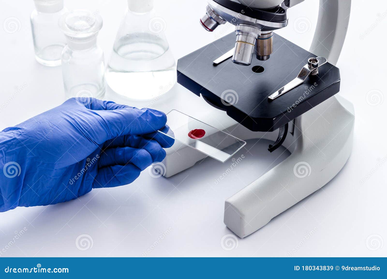 bood testing with microscope in laboratory. sample in hands on white background