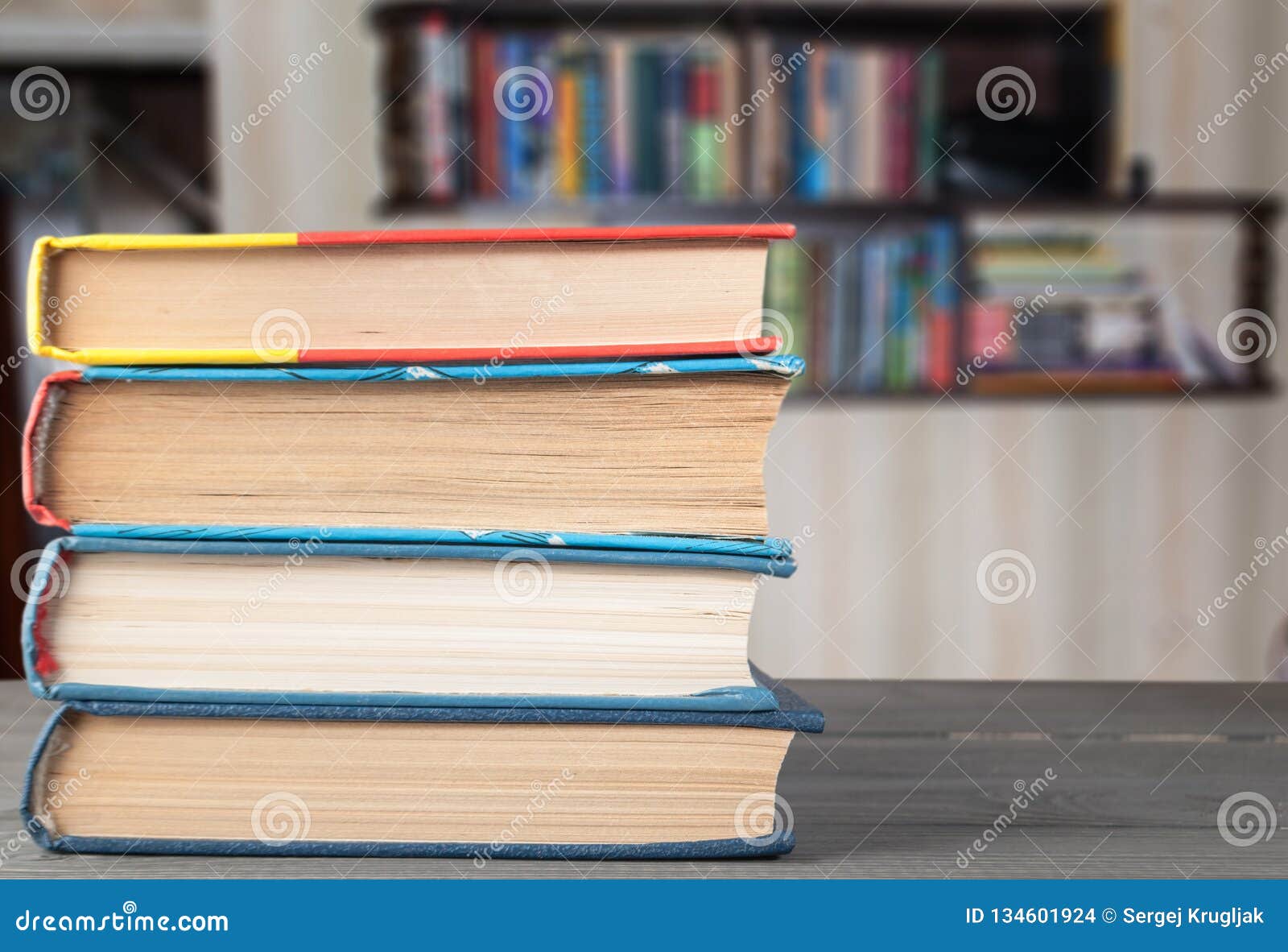 Books On The Table On The Background Of A Bookshelf Stock Photo