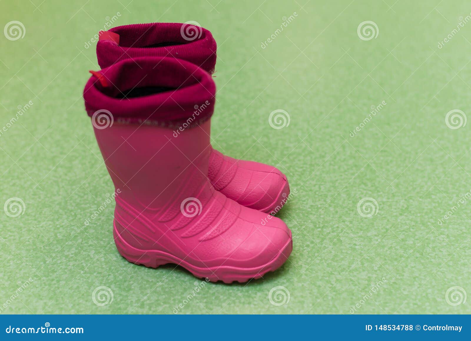 Botas De Goma Rosa Para Niños En El Suelo Verde Zapatos De Lluvia Para Niños Foto de - Imagen de zapatos, estilo: 148534788