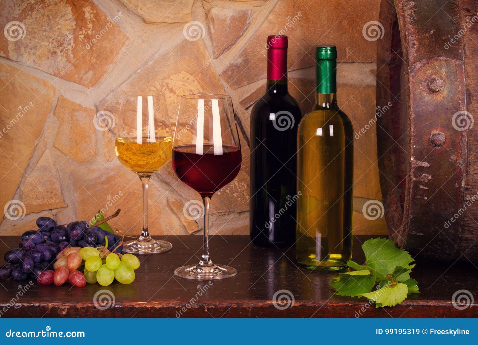 Botellas y vidrios de rojo y de blanco en la bodega, barril de vino viejo. Botellas y vidrios de vino blanco rojo y con la uva en la bodega, barril de vino viejo Comida y concepto de las bebidas