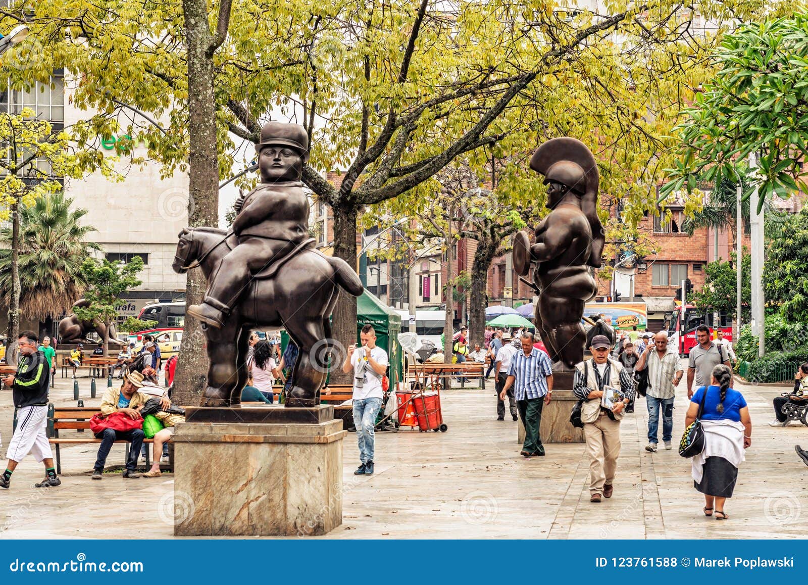 Botero sculptures located at Botero sculptures square in Medellin, Colombia. Medellin, Colombia, March 24, 2018: Tourists walking by Botero sculptures located at Botero Plaza in Medellin, Colombia. He donated 23 sculptures to town, it is the most visited place by tourists.