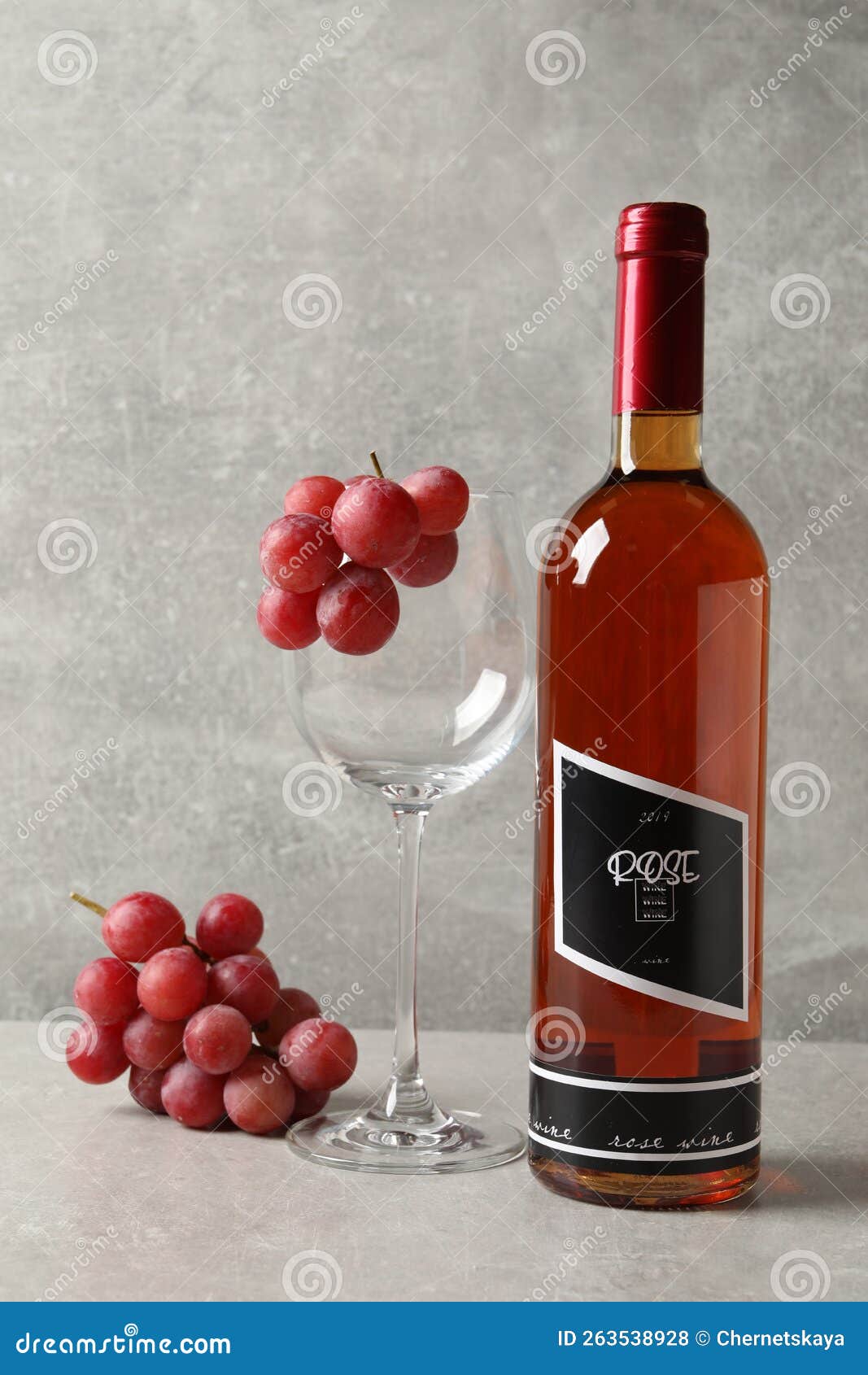 Bottle of Delicious Rose Wine, Glass and Grapes on Light Grey Table