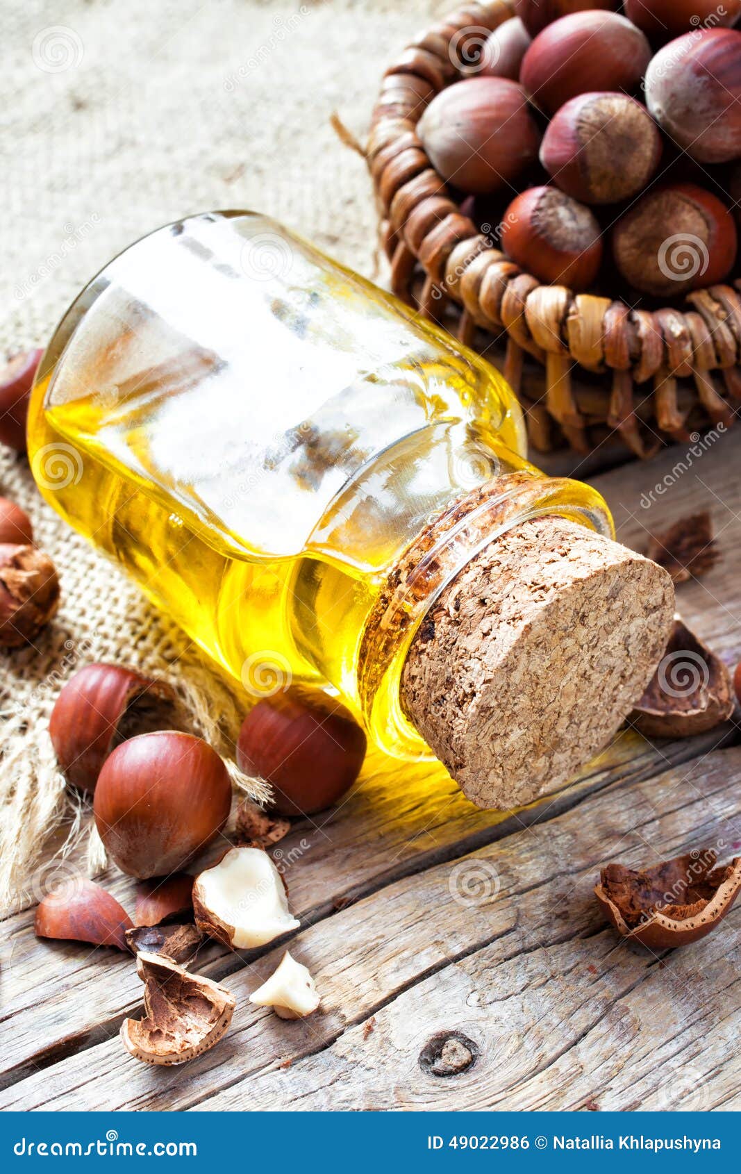 Bottle of Healthy Nut Oil and Basket with Hazelnuts on Table Stock