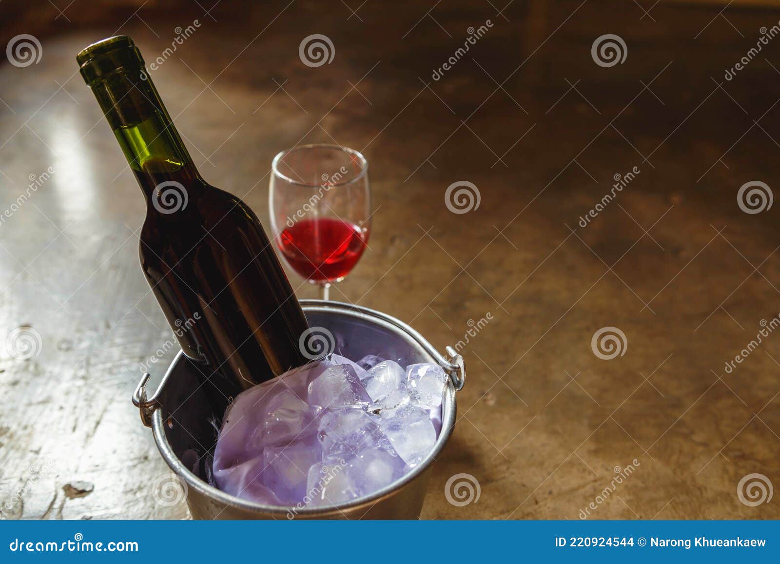 Bottle of Red Wine in an Ice Bucket and a Glass of Red Wine Stock Photo