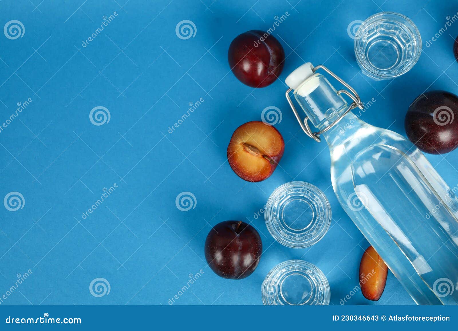 Bottle and Shots of Plum Vodka and Ingredients on Blue Background Stock