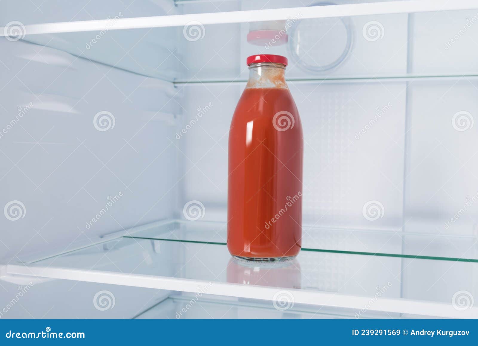 A Bottle of Tomato Juice Stands on a Shelf in an Open Refrigerator
