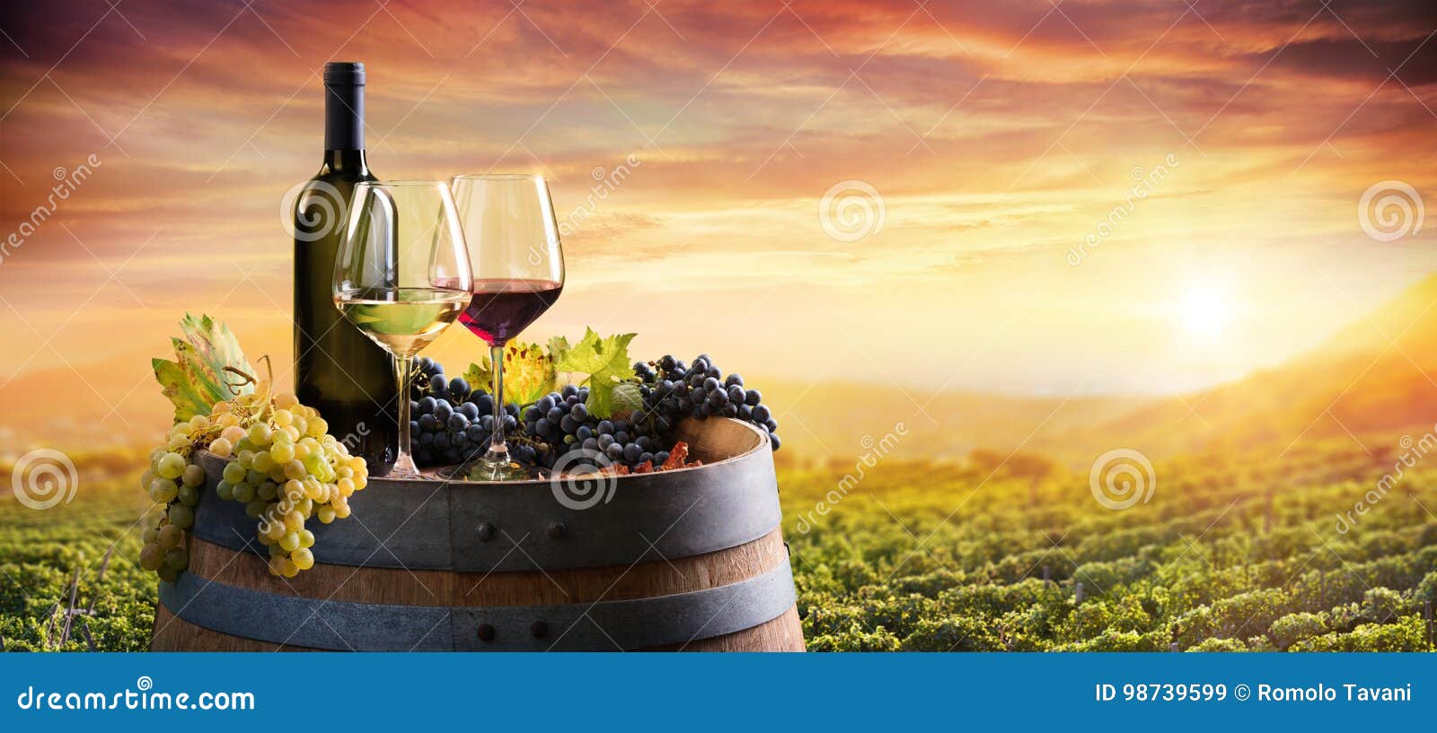 bottle and wineglasses on barrel in vineyard