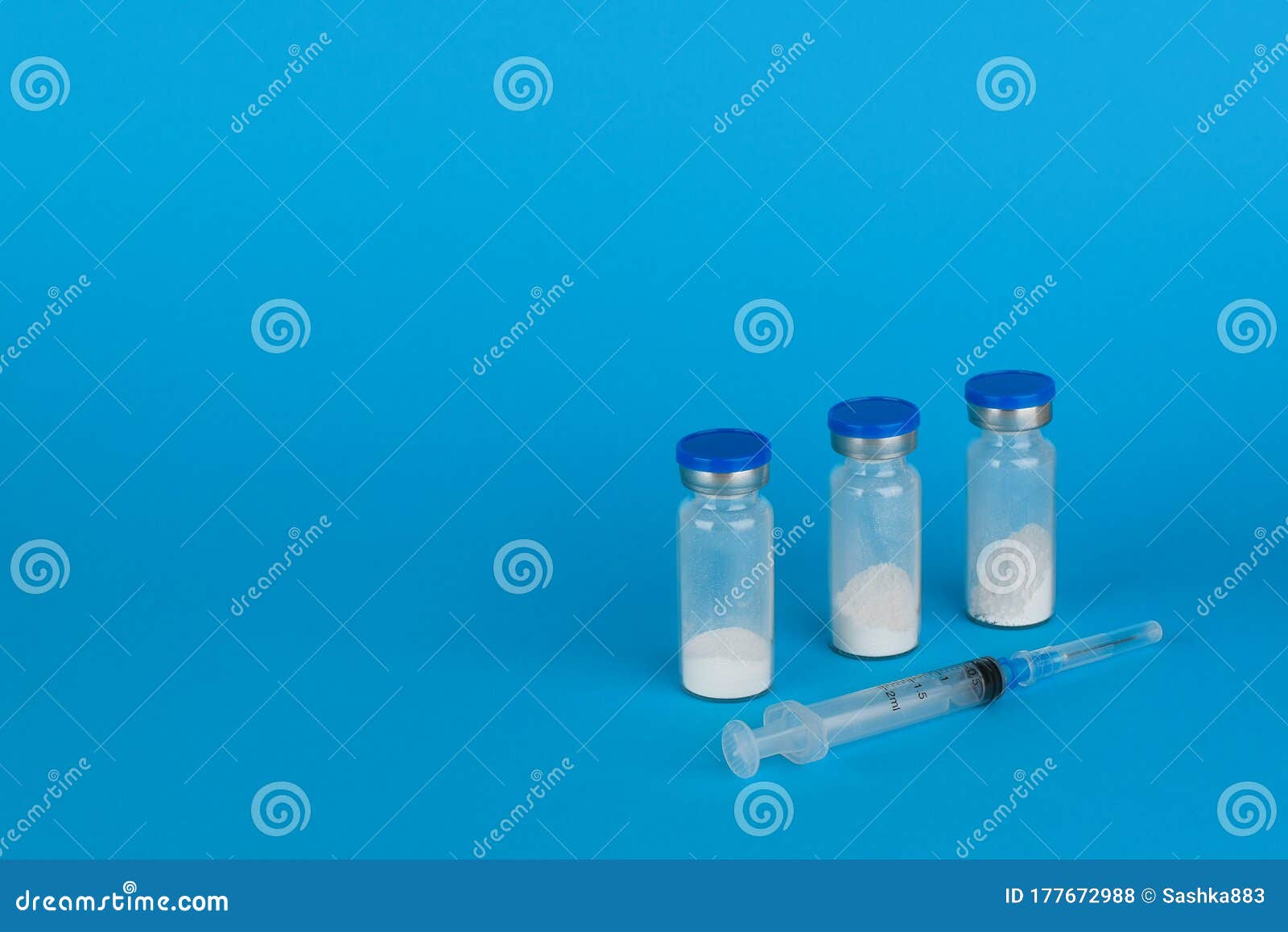 Bottles with Antibiotic Solution and Syringe on a Blue Background